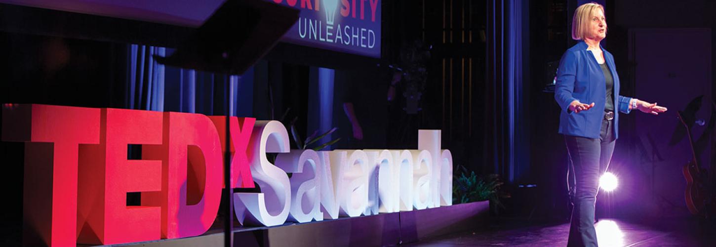 woman standing in front of TedxSavannah sign