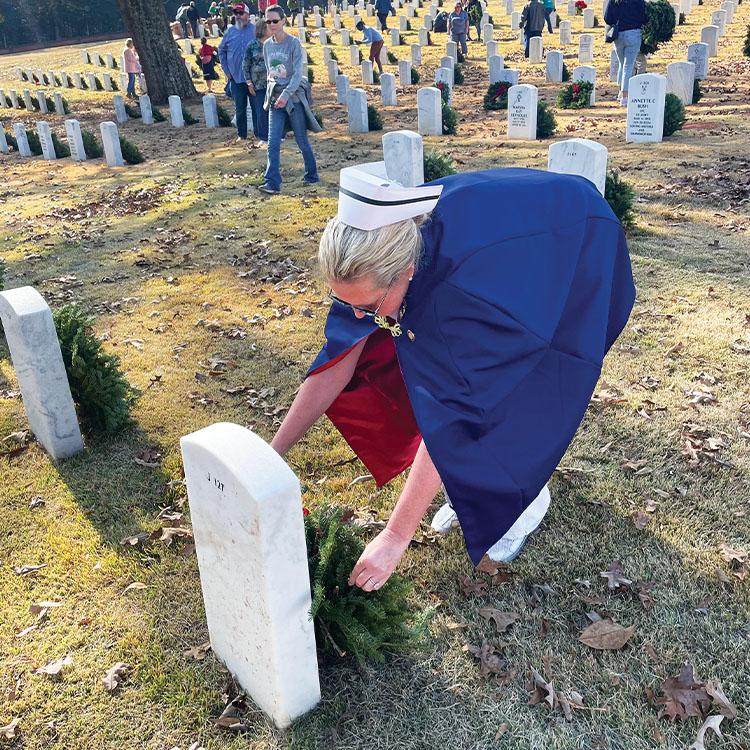 woman placing a candle on grave