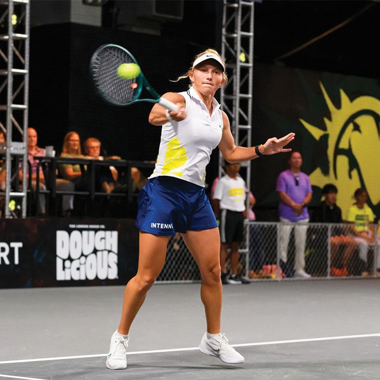 woman hits tennis ball on court