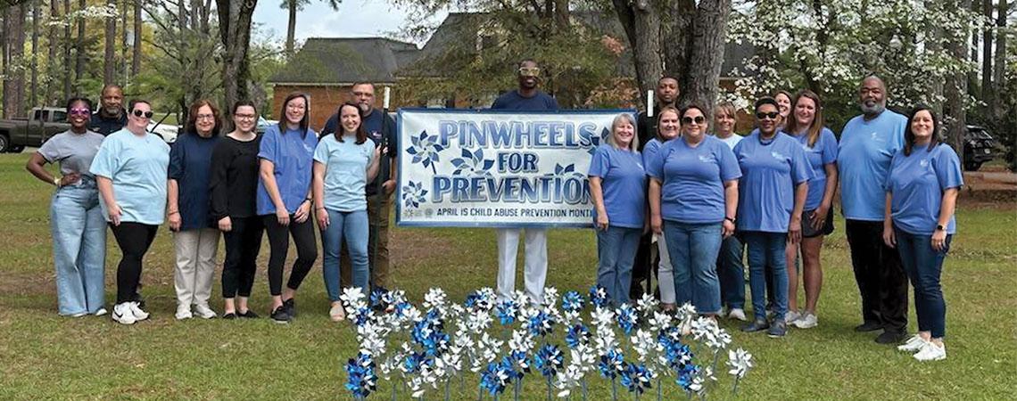 people pose with "pinwheels for prevention" sign