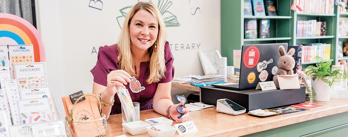 woman poses at cash register of business